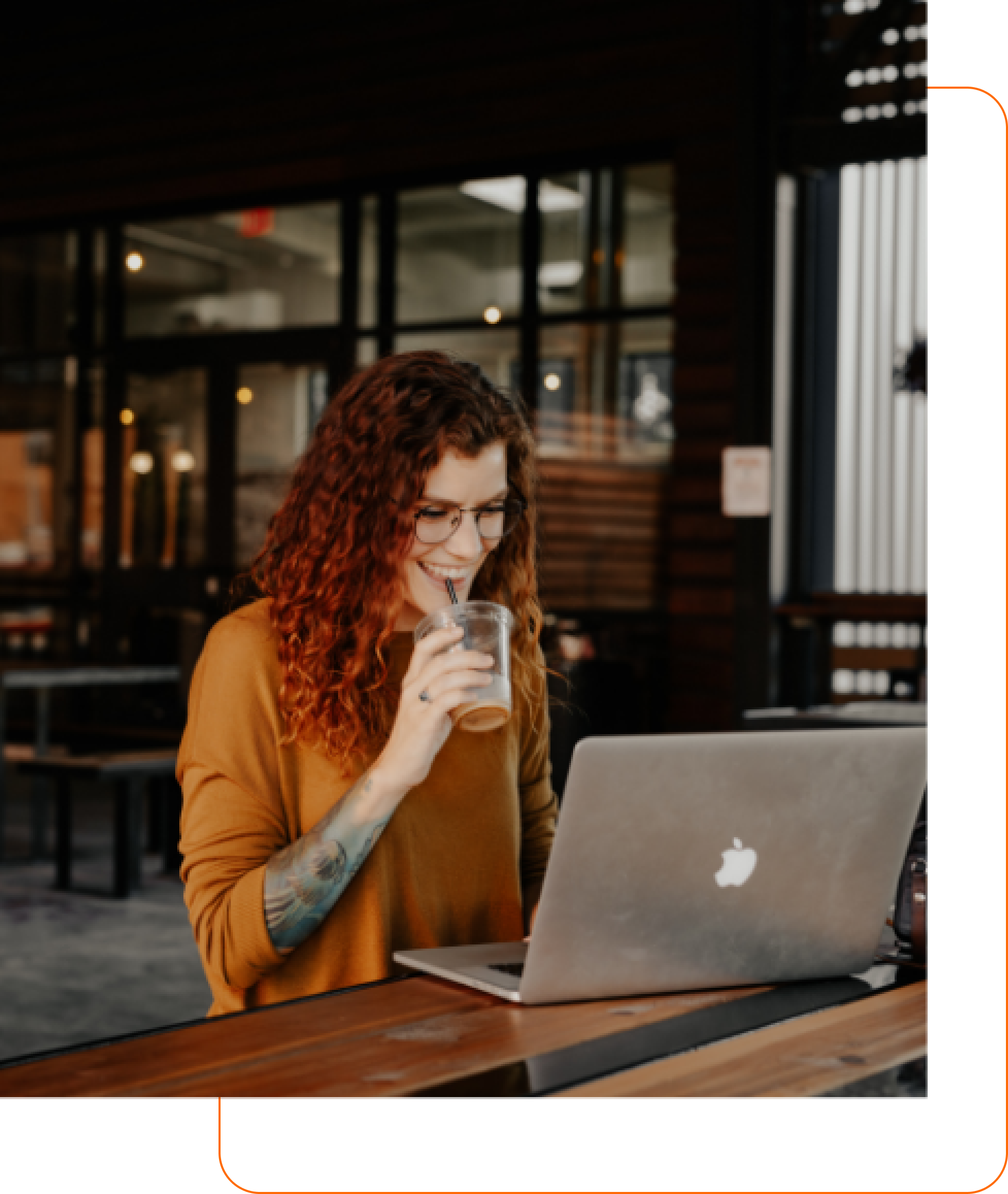 Detalhe do site Mycapital Professional -  Mulher sorridente tomando chá gelado olhando para tela de notebook.​